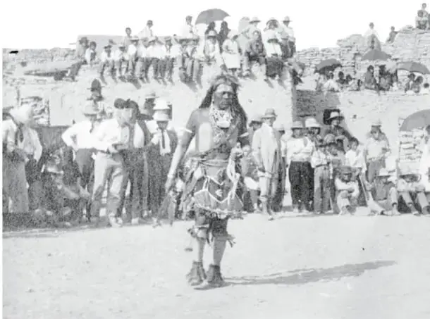Fotografía antigua titulada «Danza de mujeres hopis»: fila de mujeres sentadas formando un arco en terreno abierto.
