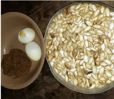 Fotografía de un plato con huevo sancochado, pinole y una fuente con semillas tostadas de calabaza, elementos usados en la ceremonia.