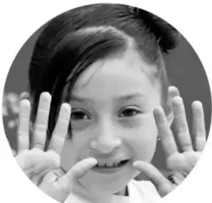 Fotografía en blanco y negro de una niña sonriendo y mostrando las manos abiertas.