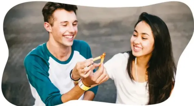 Fotografía de una joven pareja sonriente compartiendo comida.
