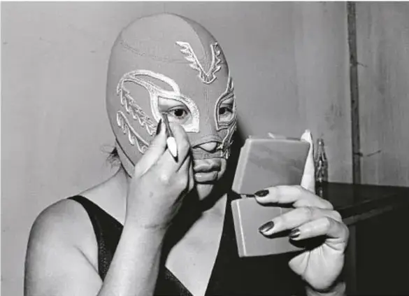 Fotografía en blanco y negro de La Venus, luchadora enmascarada, retocándose el maquillaje frente a un espejo, de la serie La Doble Lucha, 1982-1983.