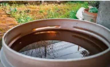 Fotografía de un recipiente de barro o tina con agua, colocado al aire libre, que ilustra el almacenamiento y reutilización del agua en la comunidad.