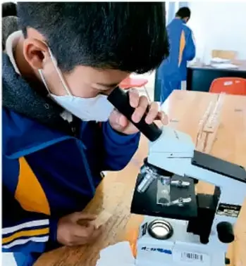 Estudiante con cubrebocas observando al microscopio en un laboratorio escolar (crédito: Luis Eduardo García Medel, Tlaxcala).