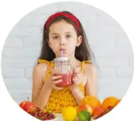 Niña con un vaso de licuado rodeada de frutas, ilustra autocuidado.