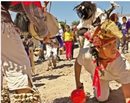 Personas con tambores, sonajas y vestuario tradicional en un espacio abierto.