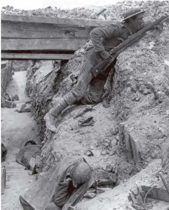 Fotografía en blanco y negro de soldados en una trinchera durante la Primera Guerra Mundial; uno de ellos apunta con un fusil mientras otro está agachado.