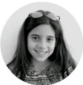 Fotografía circular en blanco y negro de una niña sonriente de cabello largo con lentes sobre la cabeza.