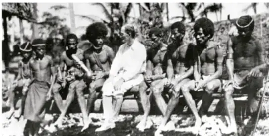 Fotografía en blanco y negro de un investigador (antropólogo) sentado en medio de un grupo indígena, ilustrando la observación participante en estudios etnográficos.