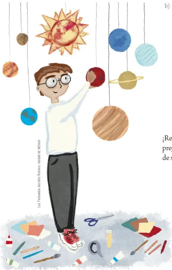 Niño con lentes observando un móvil del Sistema Solar con esferas colgantes de distintos colores (Sol, planetas) y materiales de manualidad en el suelo.