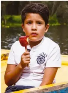 Anselmo, niño que sostiene y come una paleta al aire libre.