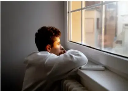 Fotografía de una joven apoyada en una ventana, en actitud reflexiva, ilustrando el proceso de autoconocimiento.