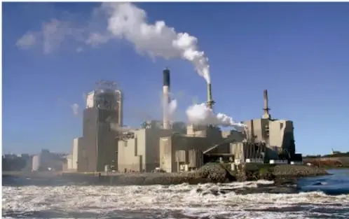 Fotografía de una planta industrial a orillas del mar, con chimeneas que emiten vapor blanco, como ejemplo de proceso productivo con impacto ambiental.