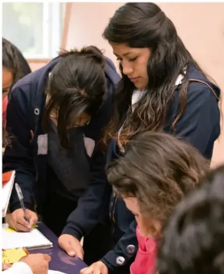 Fotografía de estudiantes de secundaria trabajando en equipo alrededor de una mesa, tomando notas y revisando documentos durante la fase de reconocimiento del proyecto.