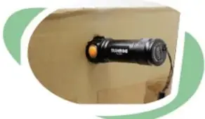 Linterna de pilas encajada en el orificio de la pared de una caja de cartón.