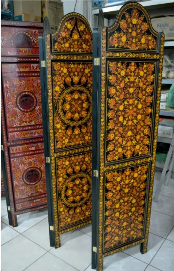 Escaparate con muebles y biombos de madera tallada y pintada con motivos florales amarillos y anaranjados sobre fondo negro, de estilo artesanal mexicano.