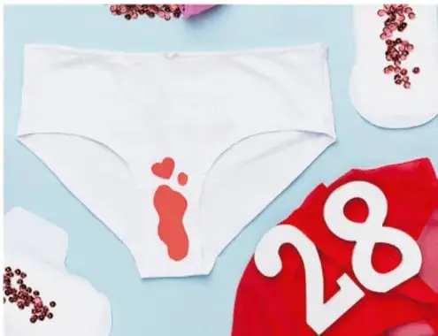 Ropa interior blanca con una marca roja, toalla sanitaria y el número 28 sobre fondo rojo, alusivo al ciclo menstrual.