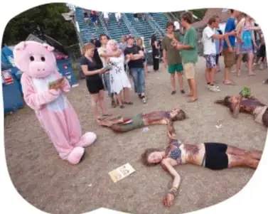 Fotografía de un happening al aire libre: personas tumbadas en el suelo, un personaje con disfraz de oso rosa y un grupo de espectadores observando.