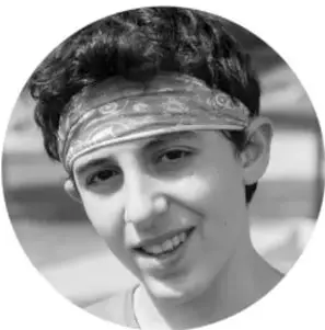 Fotografía en blanco y negro de un niño sonriente con una banda en la cabeza.