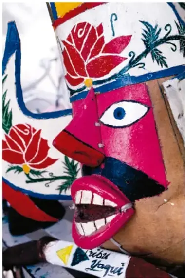 Taller artesanal: máscaras de rostros serenos en distintas etapas de acabado sobre la mesa, junto a gubias y formones.