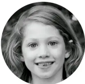 Fotografía en blanco y negro de una niña sonriente con cabello claro.