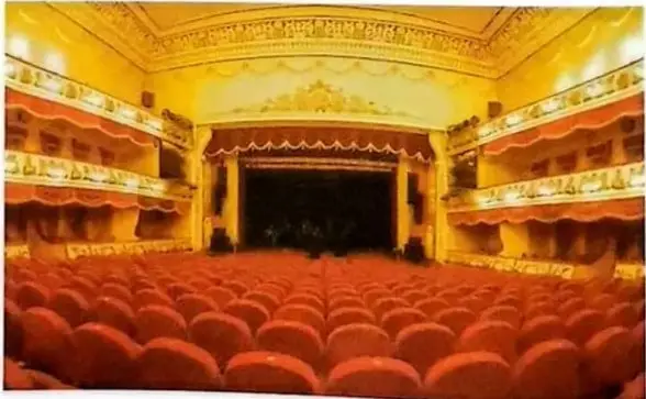 Fotografía de un teatro moderno con escenario, palcos y filas de butacas; la imagen ilustra la herencia del teatro clásico griego en los escenarios actuales.