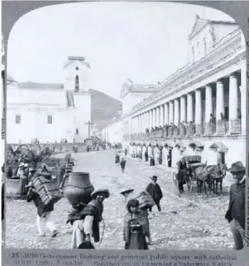 Fotografía histórica de una escena urbana de Quito a inicios del siglo XX, con una plaza, edificaciones, personas y animales.