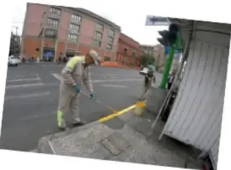 Grupo de personas caminando con costales al hombro por un camino de tierra.