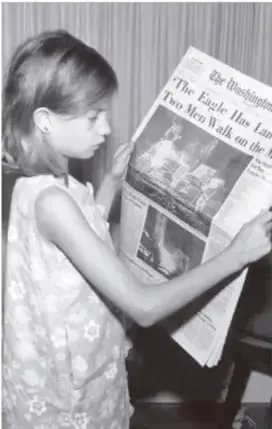 Fotografía en blanco y negro de una niña leyendo un periódico con el titular 'Two Men Walk on the Moon' (Dos hombres caminan sobre la Luna).