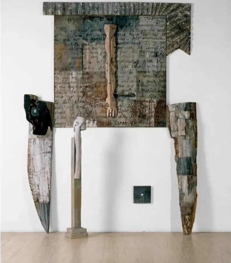 Fotografía de la instalación 'Formas violadas' (1994) de Alejandro Aguilera: una obra de gran formato con un panel central de aspecto textil escrito, del que pende un brazo de madera; a los lados, dos piezas alargadas de madera y una figura vertical central.