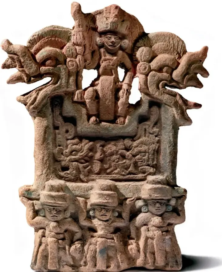 Escultura prehispánica de barro que representa figuras humanas (tres en la base) y elementos zoomorfos o deity en la parte superior, sobre un pedestal decorado.
