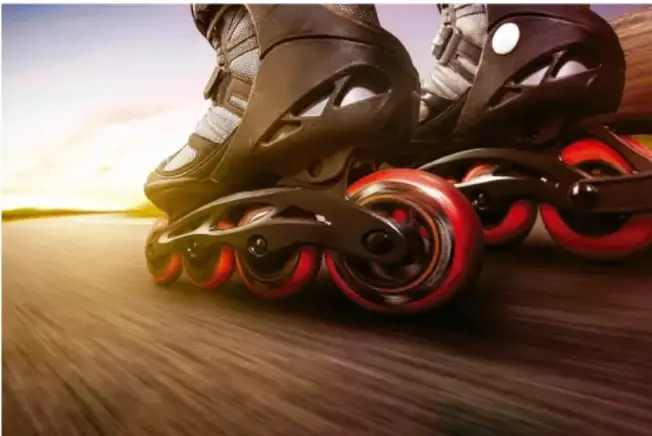 Fotografía de patines en línea (roller) en movimiento sobre una superficie con efecto de velocidad al atardecer.