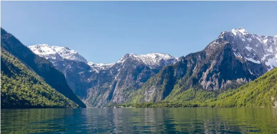 Paisaje de montañas nevadas y lago de agua líquida, que muestra los estados sólido y líquido del agua en la naturaleza.