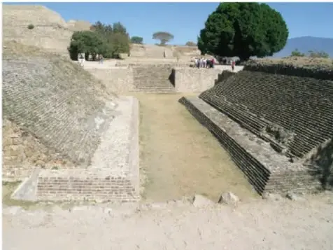 Fotografía de una cancha de juego de pelota mesoamericana con escalinatas y estructura de piedra.