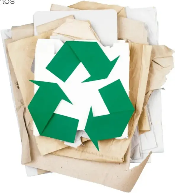 Fotografía de papeles usados amontonados (cartulinas, papel kraft y hojas blancas) con un símbolo verde de reciclaje en el centro.