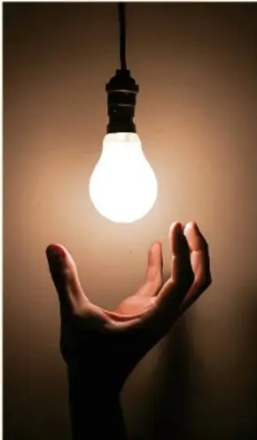 Mano sosteniendo un foco encendido, símbolo de ideas y energía.
