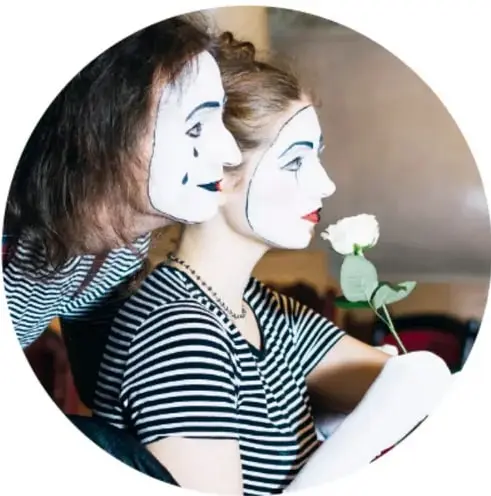 Fotografía circular de dos mimos con maquillaje blanco, vestuario de rayas, mirando hacia la derecha; uno sostiene una flor blanca.