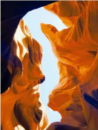 Fotografía a color del Antelope Canyon, Arizona, EE. UU., con paredes de roca naranja y una abertura de luz.