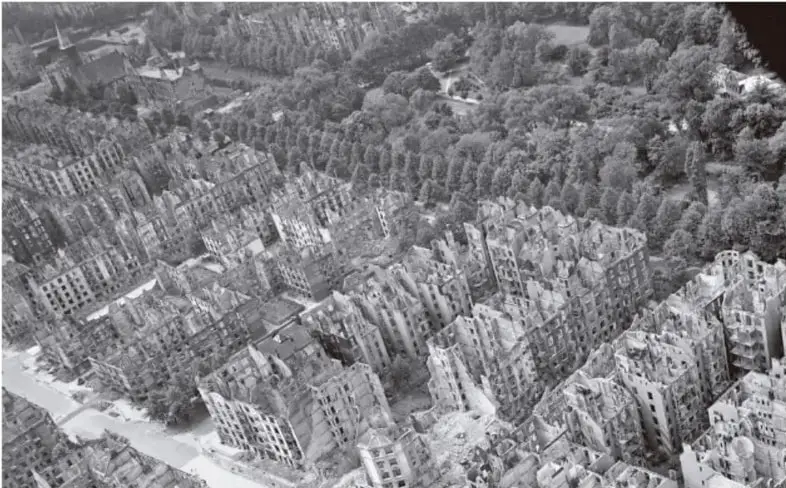 Fotografía aérea en blanco y negro de una ciudad europea devastada por los bombardeos de la Primera Guerra Mundial. Se observan edificios destruidos, calles en ruinas y zonas boscosas alrededor. La imagen ilustra la magnitud de la destrucción material que dificultó la recuperación económica de posguerra.