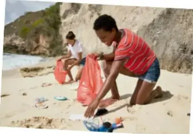 Personas recogiendo basura en una playa, mostrando cuidado del ambiente.