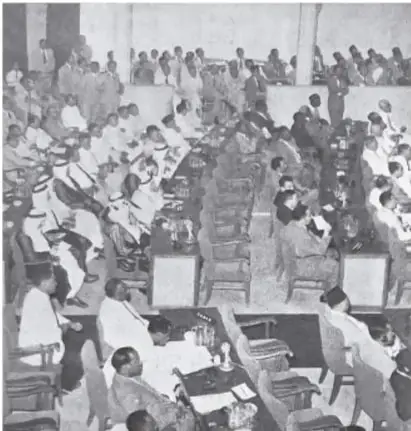 Fotografía en blanco y negro de una asamblea numerosa, posiblemente la Conferencia de Bandung, con participantes sentados en filas.