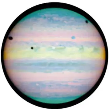 Planeta Júpiter con bandas de colores pastel y pequeños puntos oscuros sobre su superficie (sombras de sus lunas).