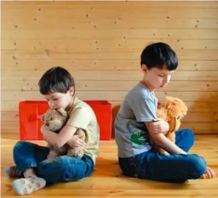 Dos niños sentados en el piso abrazando peluches, ilustrando una situación de conflicto entre pares.