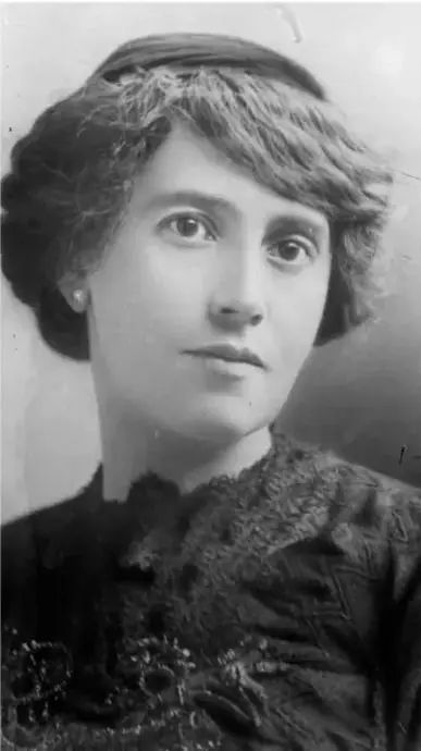 Fotografía en blanco y negro de una mujer joven de principios del siglo XX, con cabello corto ondulado y vestimenta oscura con encaje; retrato de perfil tres cuartos.