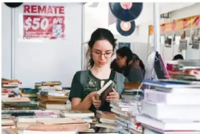 Fotografía de estudiantes consultando y leyendo libros en una biblioteca o librería; en el fondo se observa un cartel que dice REMATE $50.