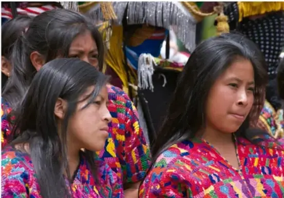 Fotografía de mujeres y niñas indígenas con ropas tradicionales de colores vivos (huipiles), en un entorno comunitario, ilustrando la diversidad cultural y lingüística de México.