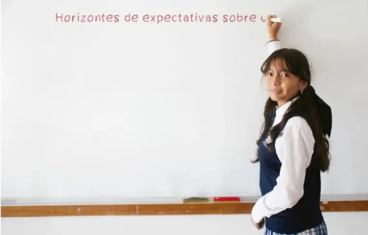 Fotografía de una estudiante escribiendo en el pizarrón el título 'Horizontes de expectativas sobre u...'